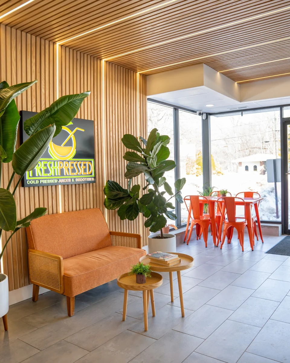 Inside Fresh Pressed in Plantsville, with orange chairs, a sunny window and green plants